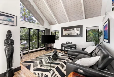 a living room with furniture a flat screen tv and a floor to ceiling window
