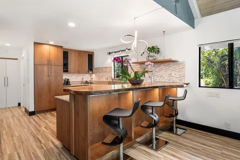a kitchen with stainless steel appliances granite countertop a table chairs in it and wooden floors