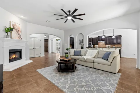 a living room with furniture a fireplace and a ceiling fan