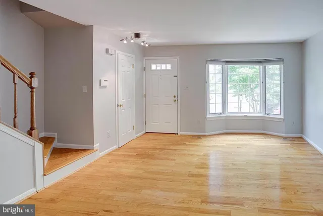 a view of an empty room with window and wooden floor