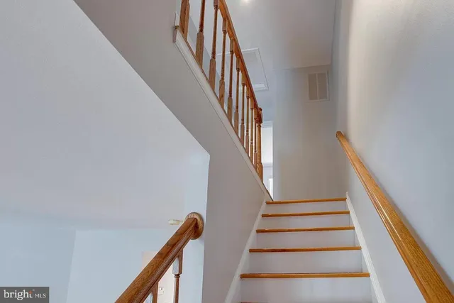 a view of a hallway with wooden floor and a bathroom