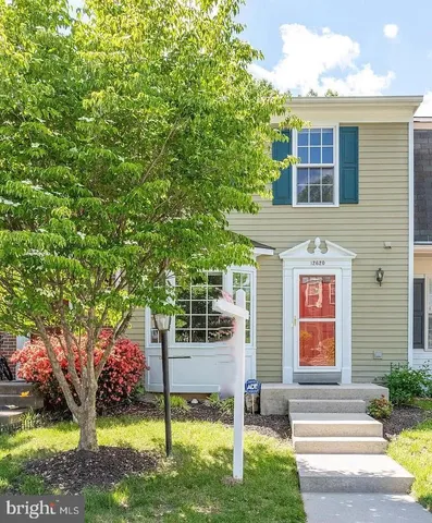 a front view of a house with a garden and trees