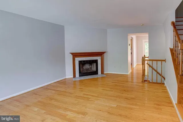 a view of an empty room with wooden floor and a fireplace
