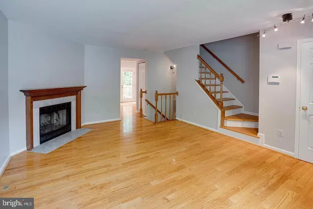 a view of an empty room with wooden floor and a fireplace