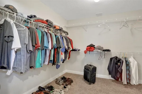 a walk in closet with clothes and shoes