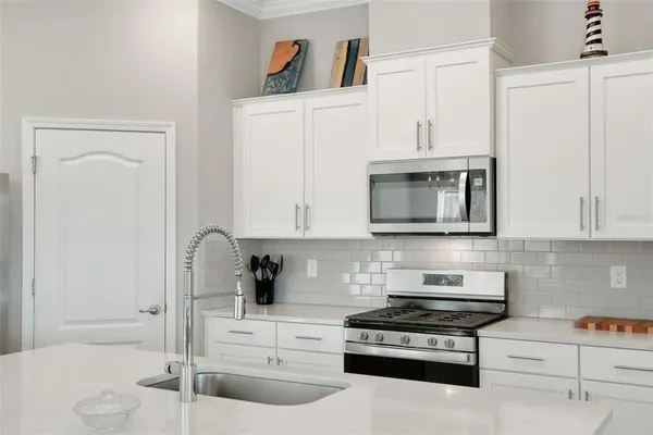 a kitchen with granite countertop white cabinets and stainless steel appliances
