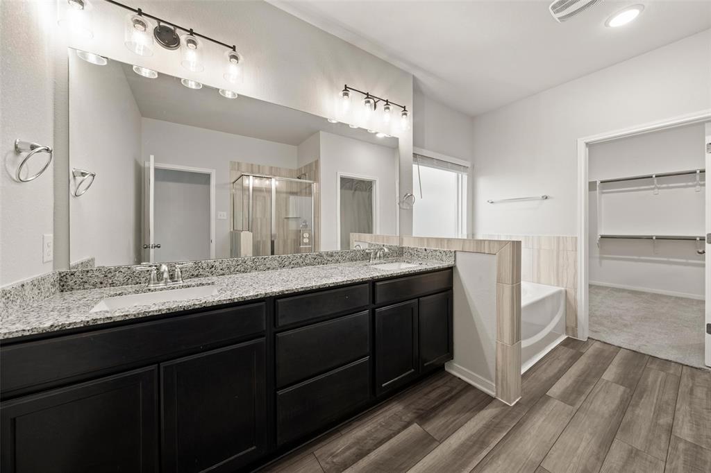 11304 Solar Street Lorena, TX 76655 - Photo 16 of 34 Bathroom with a spacious closet, a stall shower, a garden tub, double vanity, and wood tiled floors