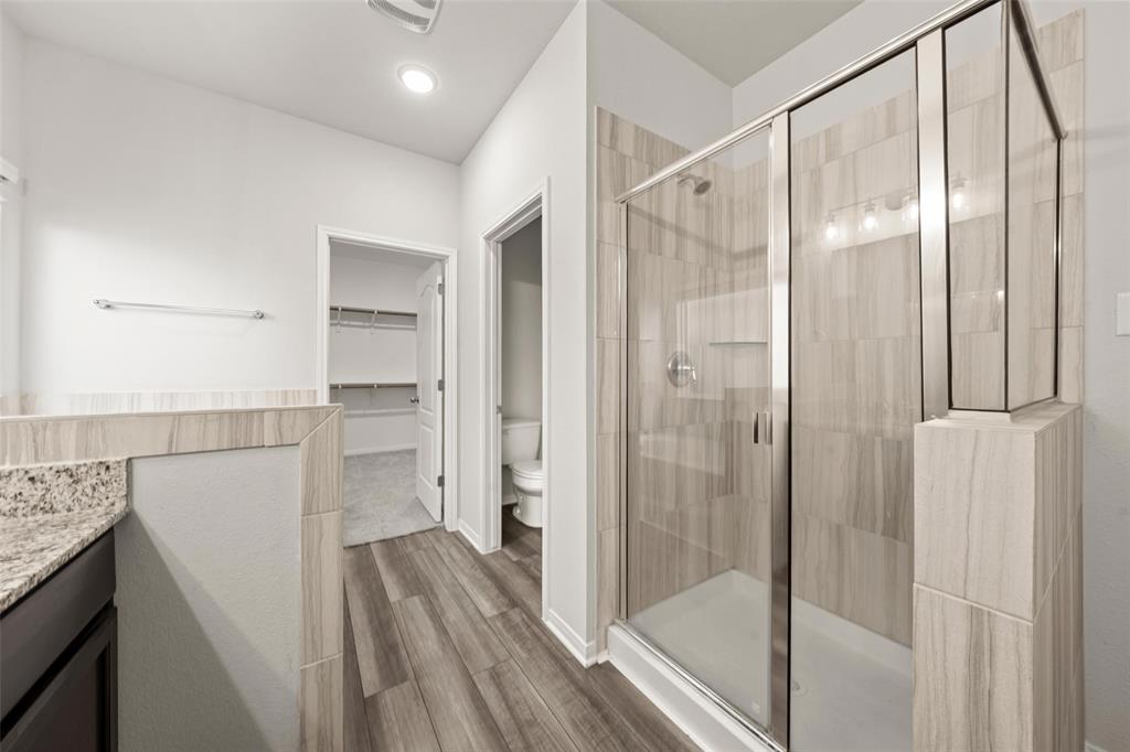 11304 Solar Street Lorena, TX 76655 - Photo 17 of 34 Full bath featuring a spacious closet, vanity, a stall shower, and dark wood-type flooring