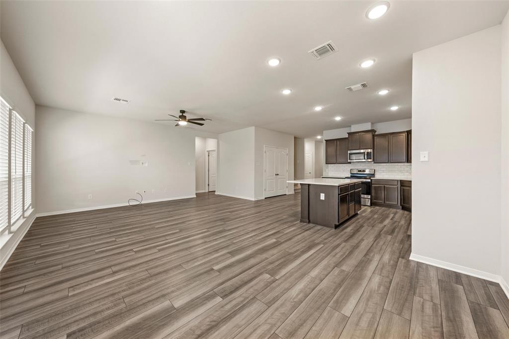 11304 Solar Street Lorena, TX 76655 - Photo 31 of 34 Kitchen with dark brown cabinets, open floor plan, a center island, stainless steel appliances, and dark wood-style flooring