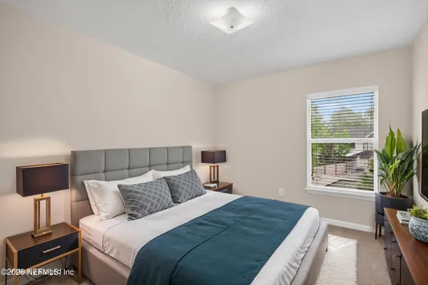 a bedroom with a bed a flat screen tv and a window