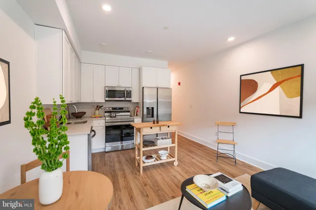 a living room with furniture potted plant and kitchen view