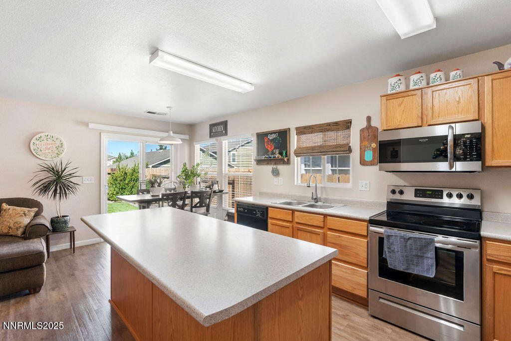 7685 Bichon Street Reno, NV 89506 - Photo 9 of 29 a kitchen with stainless steel appliances granite countertop a stove top oven a sink a dining table and chairs with wooden floor