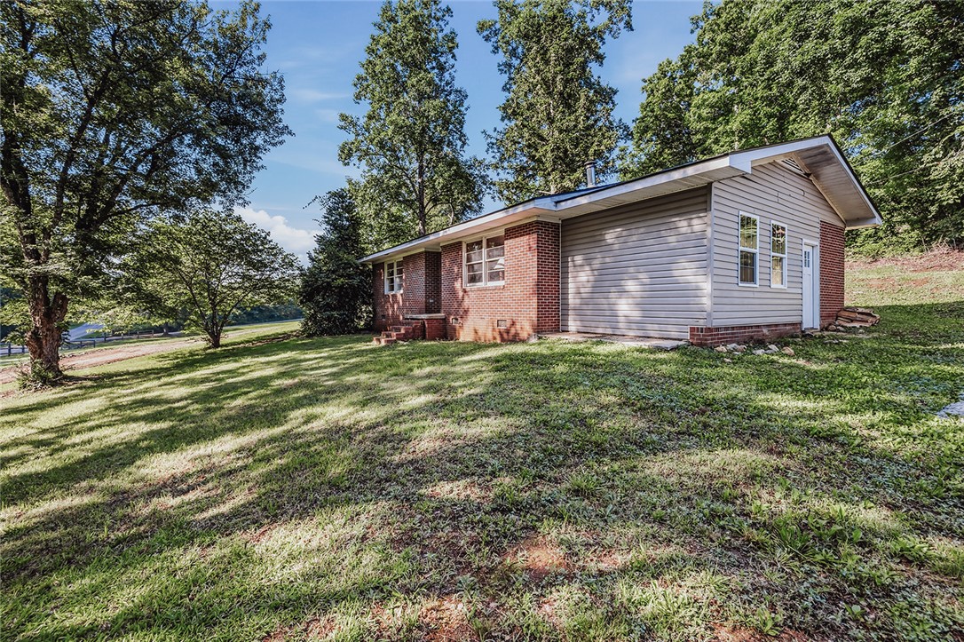 209 Cleveland Pike Road Westminster, SC 29693 - Photo 26 of 30 A classic brick and siding residence rests on a verdant, sloping lot, framed by mature trees.
