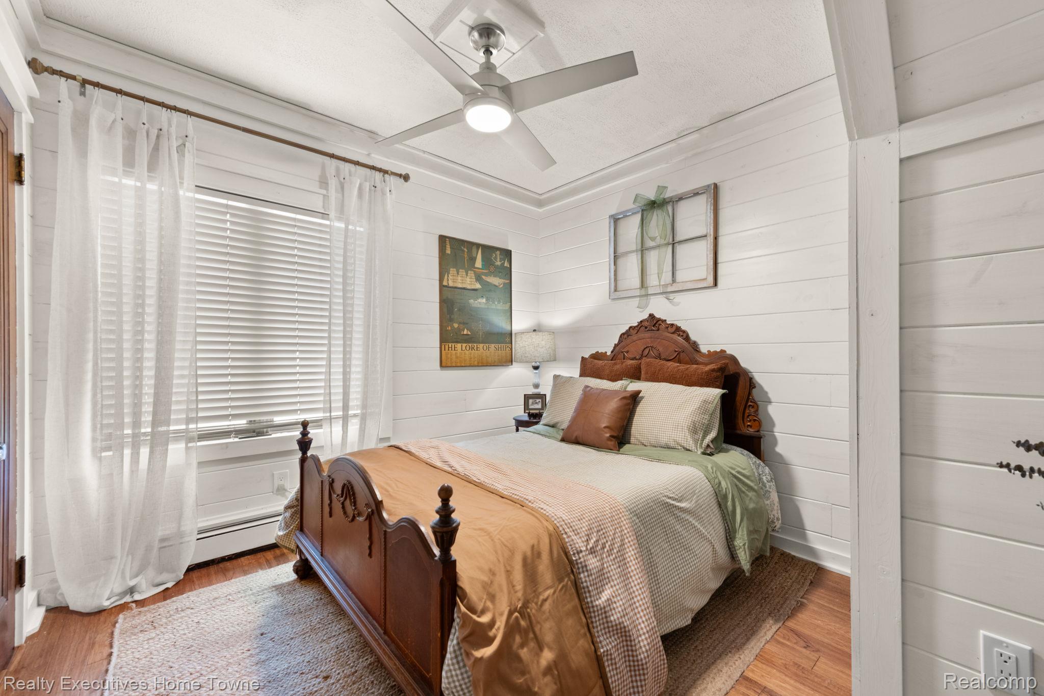 8308 Lakeshore Road Fort Gratiot, MI 48059 - Photo 36 of 79 Bedroom featuring shiplap walls, wood-finish flooring, and a ceiling fan with integrated lighting