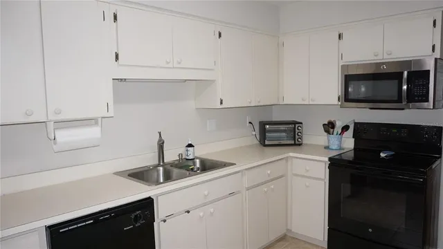 a kitchen with white cabinets a sink and white appliances