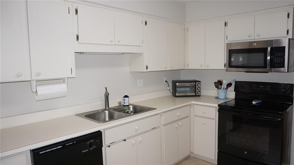 13012 Wedgewood Way, Unit A Hudson, FL 34667 - Photo 6 of 29 a kitchen with white cabinets a sink and white appliances