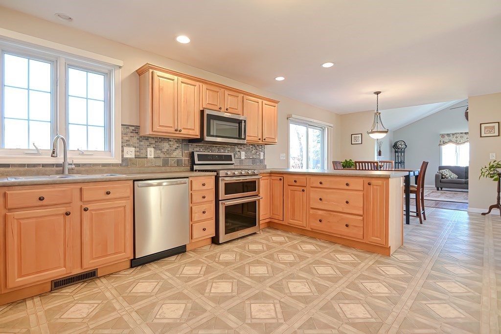 47 Hidden Road Dracut, MA 01826 - Photo 4 of 28 a kitchen with kitchen island granite countertop a stove top oven a sink a counter space and cabinets