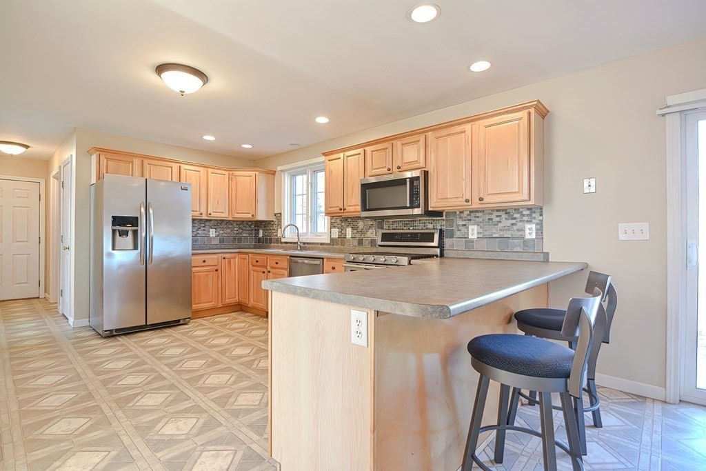 47 Hidden Road Dracut, MA 01826 - Photo 5 of 28 a kitchen with stainless steel appliances granite countertop a stove a refrigerator a sink dishwasher a dining table and chairs with wooden floor