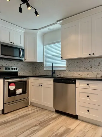 a kitchen with granite countertop white cabinets stainless steel appliances and a sink