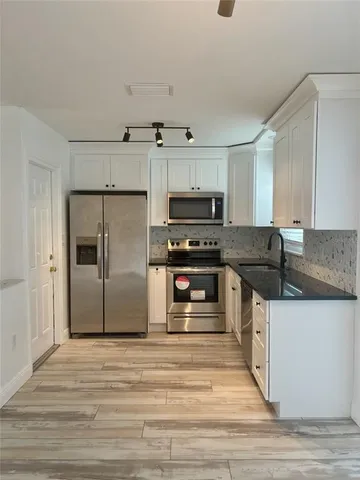a kitchen with stainless steel appliances kitchen island granite countertop a stove and a refrigerator