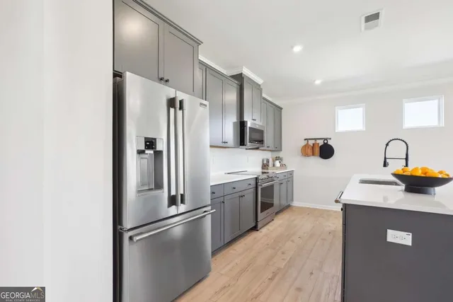 a kitchen with stainless steel appliances a refrigerator a sink a stove and cabinets