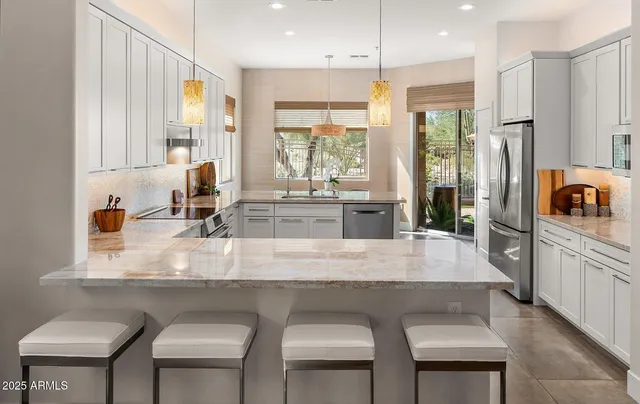 a kitchen with kitchen island granite countertop a table chairs sink and cabinets