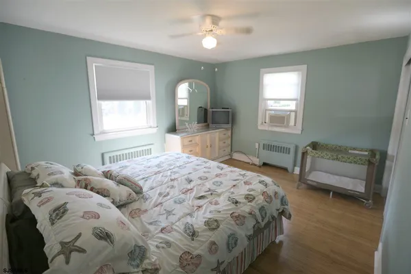 a bedroom with two beds and a dresser with wooden floor