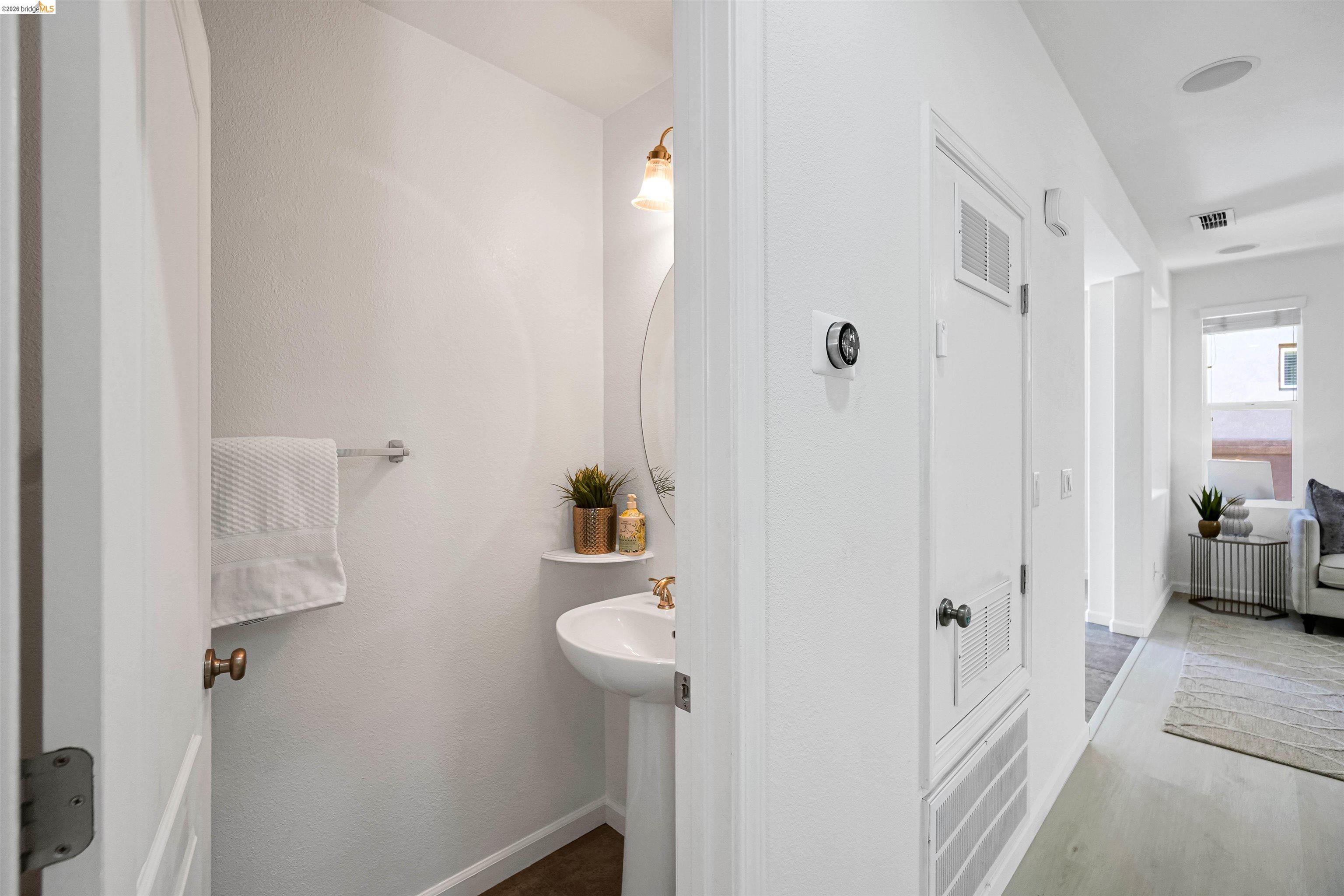 449 Constantine Court San Ramon, CA 94583 - Photo 33 of 63 Pedestal sink with brass-toned hardware, an oval mirror, and an overhead vanity light