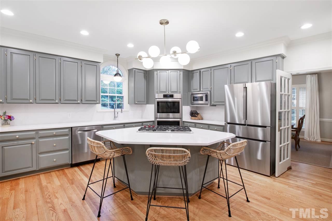 2324 Oxford Road Raleigh, NC 27608 - Photo 7 of 30 a kitchen with stainless steel appliances granite countertop a stove a refrigerator a microwave a dining table and chairs with wooden floor