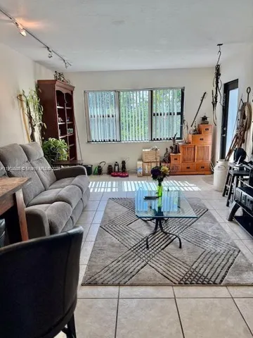 a living room with furniture hard wood floor and a floor to ceiling window