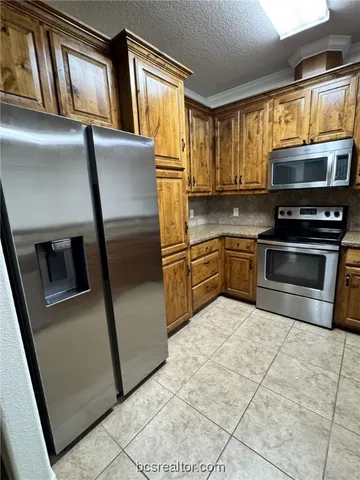 a kitchen with stainless steel appliances granite countertop a refrigerator a stove a sink and a microwave