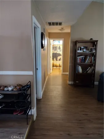 a view of a hallway with wooden floor and a bathroom