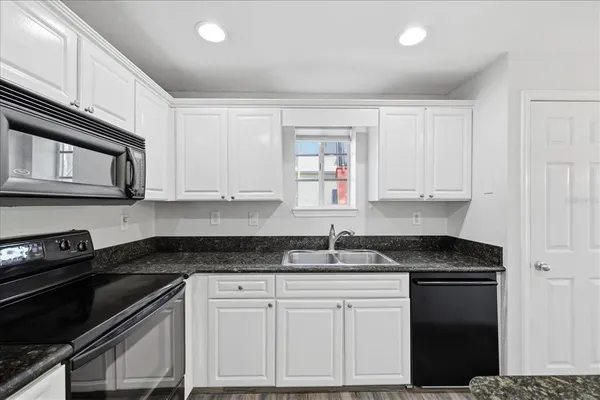 a kitchen with granite countertop white cabinets and black appliances