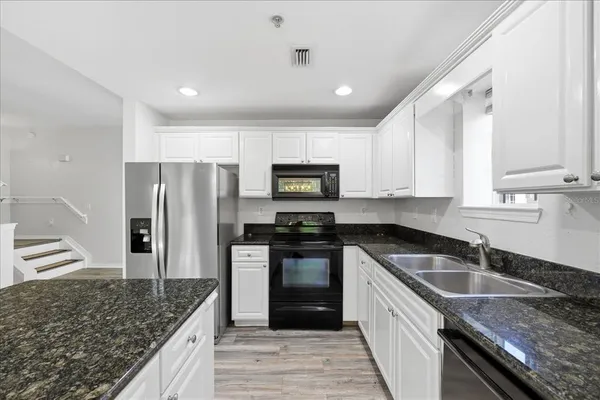 a kitchen with stainless steel appliances granite countertop a sink stove and refrigerator