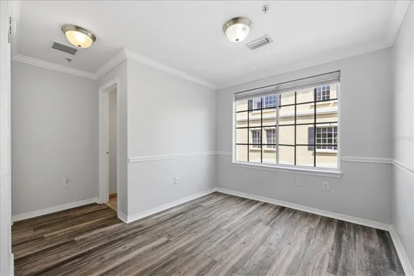 an empty room with wooden floor and windows