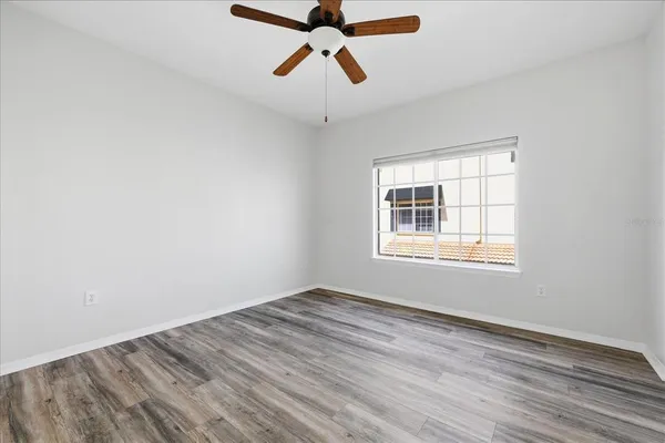 a view of empty room with wooden floor and fan