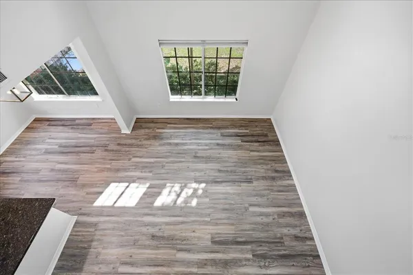 a view of an empty room with wooden floor and a window