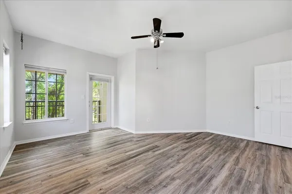 a view of empty room with wooden floor and fan