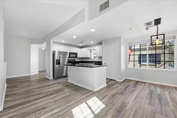 a view of kitchen with stainless steel appliances granite countertop a stove top oven a kitchen island a refrigerator and a sink with wooden floor