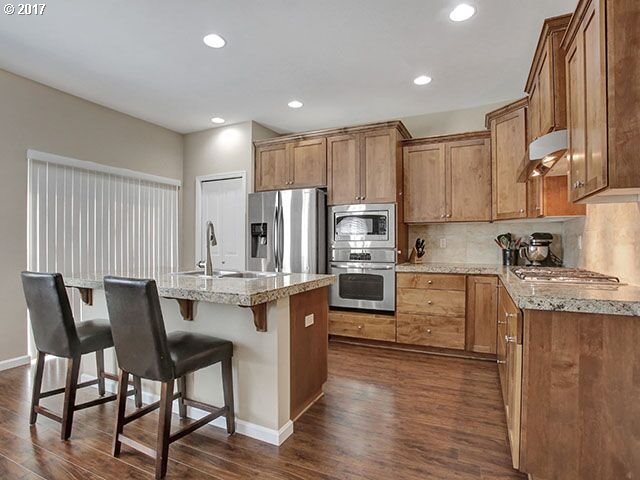 9478 Northwest Ember Lane Portland, OR 97229 - Photo 5 of 23 a kitchen with stainless steel appliances granite countertop a stove a sink a refrigerator white cabinets and wooden floor