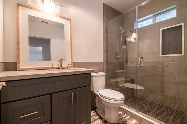 a bathroom with a sink a toilet a mirror and shower