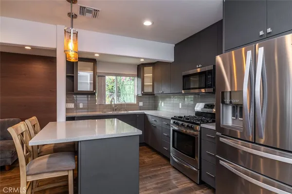 a kitchen with stainless steel appliances granite countertop a refrigerator a stove a sink dishwasher a dining table and chairs with wooden floor