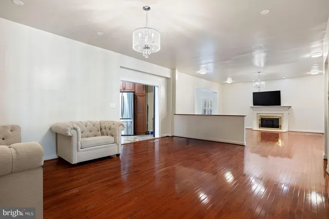 a living room with couches and kitchen view with wooden floor