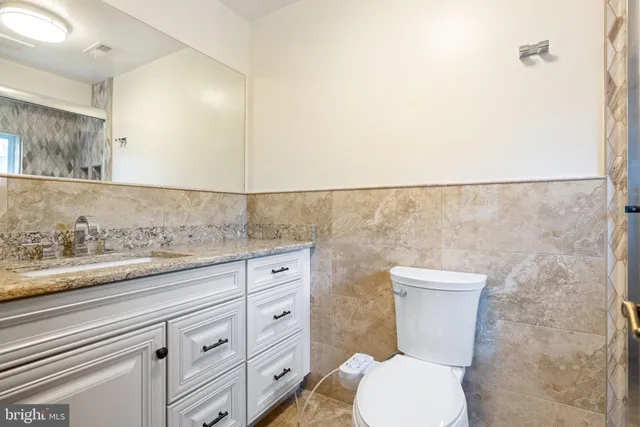 a bathroom with a granite countertop toilet and a sink