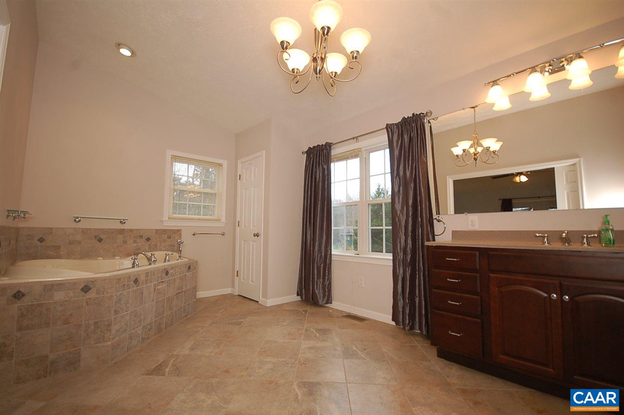 5075 Celt Road Stanardsville, VA 22973 - Photo 33 of 36 a spacious bathroom with a granite countertop sink a large mirror and a bathtub with shower