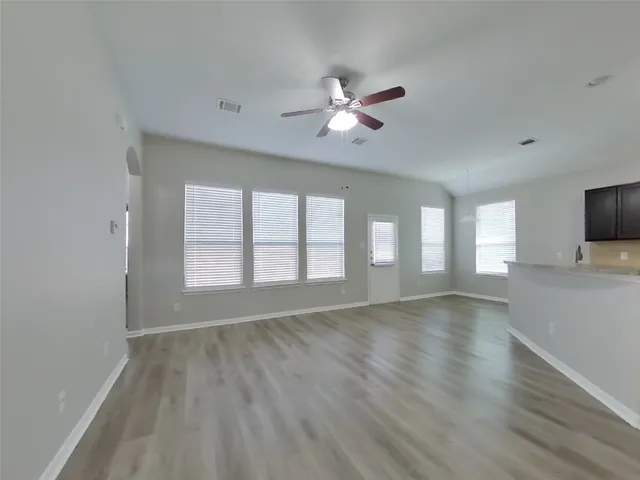 a view of an empty room with a window and wooden floor