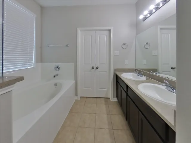a spacious bathroom with a tub sink shower and mirror