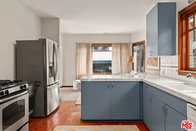 a kitchen with stainless steel appliances granite countertop a refrigerator a sink and wooden floors