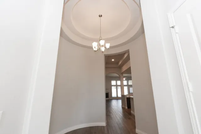 a view of a hallway with wooden floor and a chandelier