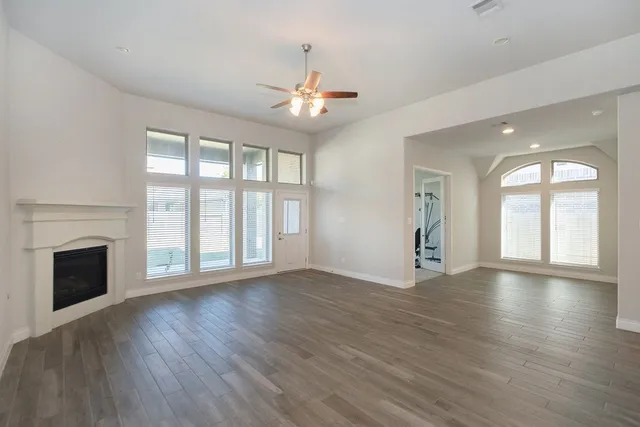 an empty room with wooden floor fireplace and windows